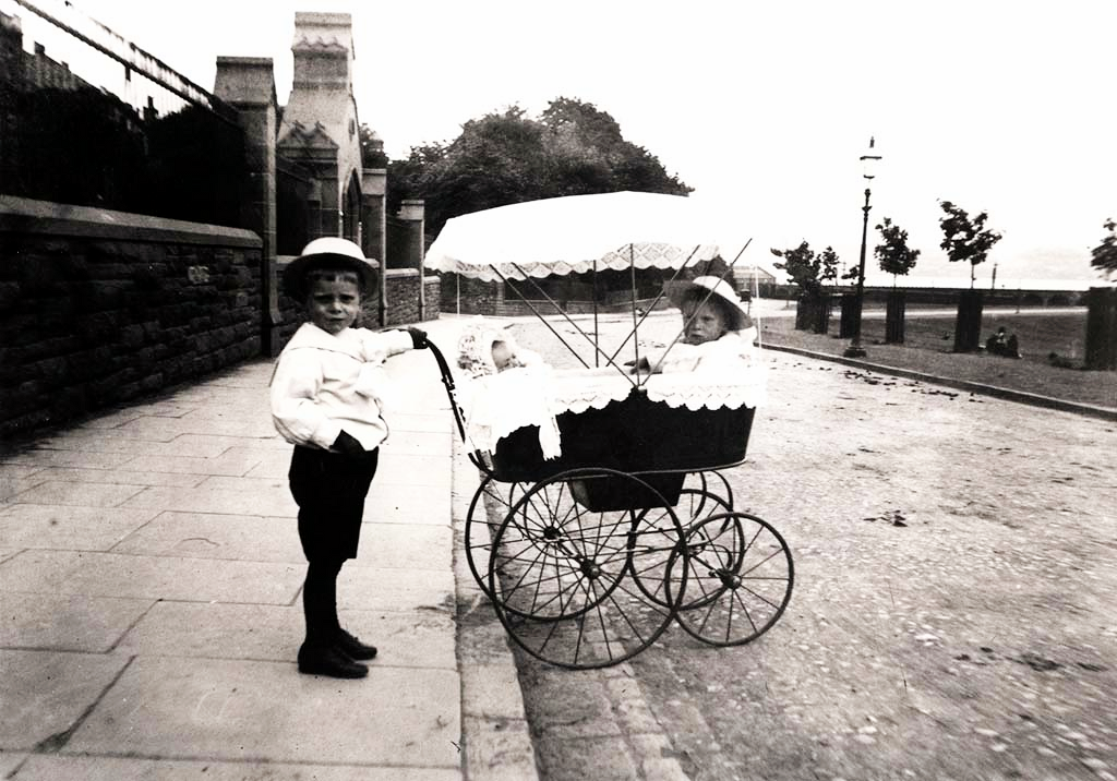 Small Boy Pushing Pram with Baby and Child in It